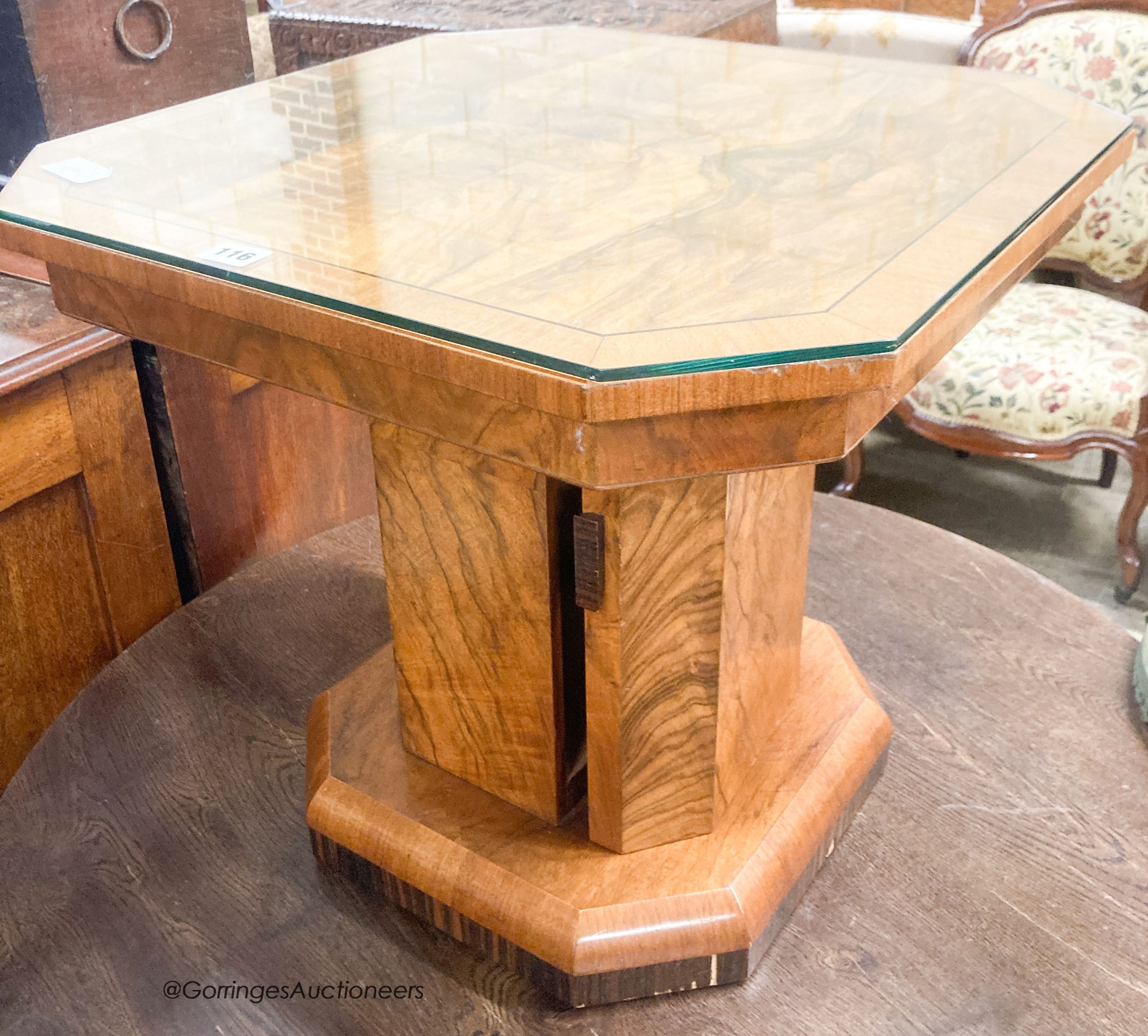 An Art Deco style octagonal figured walnut coffee table, with cupboard column, width 57cm, height 51cm